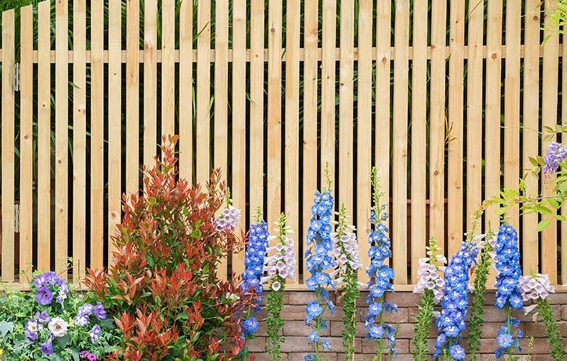 ein schöner Holzzaun auf einer Mauer mit vielen bunten Blumen