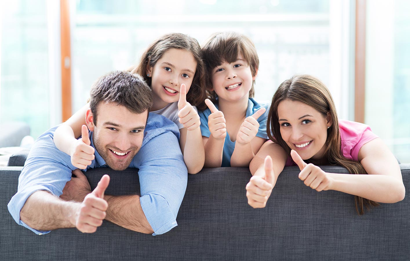 Familie mit zwei Kindern die Daumen hoch zeigen.